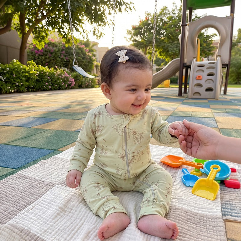 Baby sitting on a picnic blanket in the PLANTAS Kids Panda Cotton Jumpsuit in Pistage
