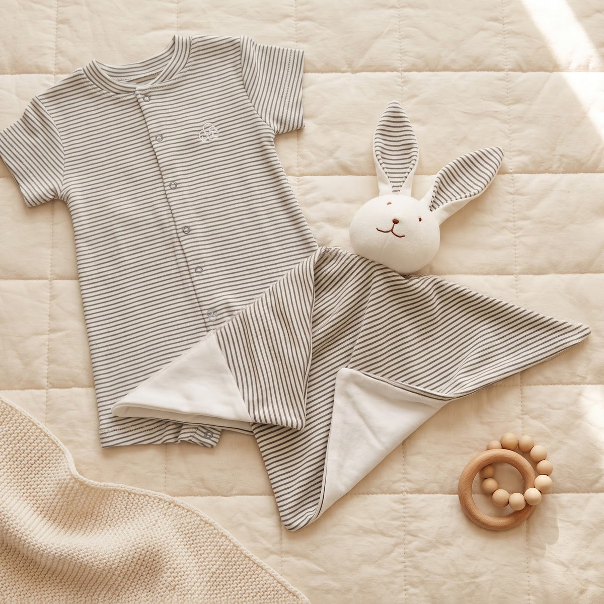 Charcoal-striped Little Bunny comforter toy displayed beside a matching striped romper