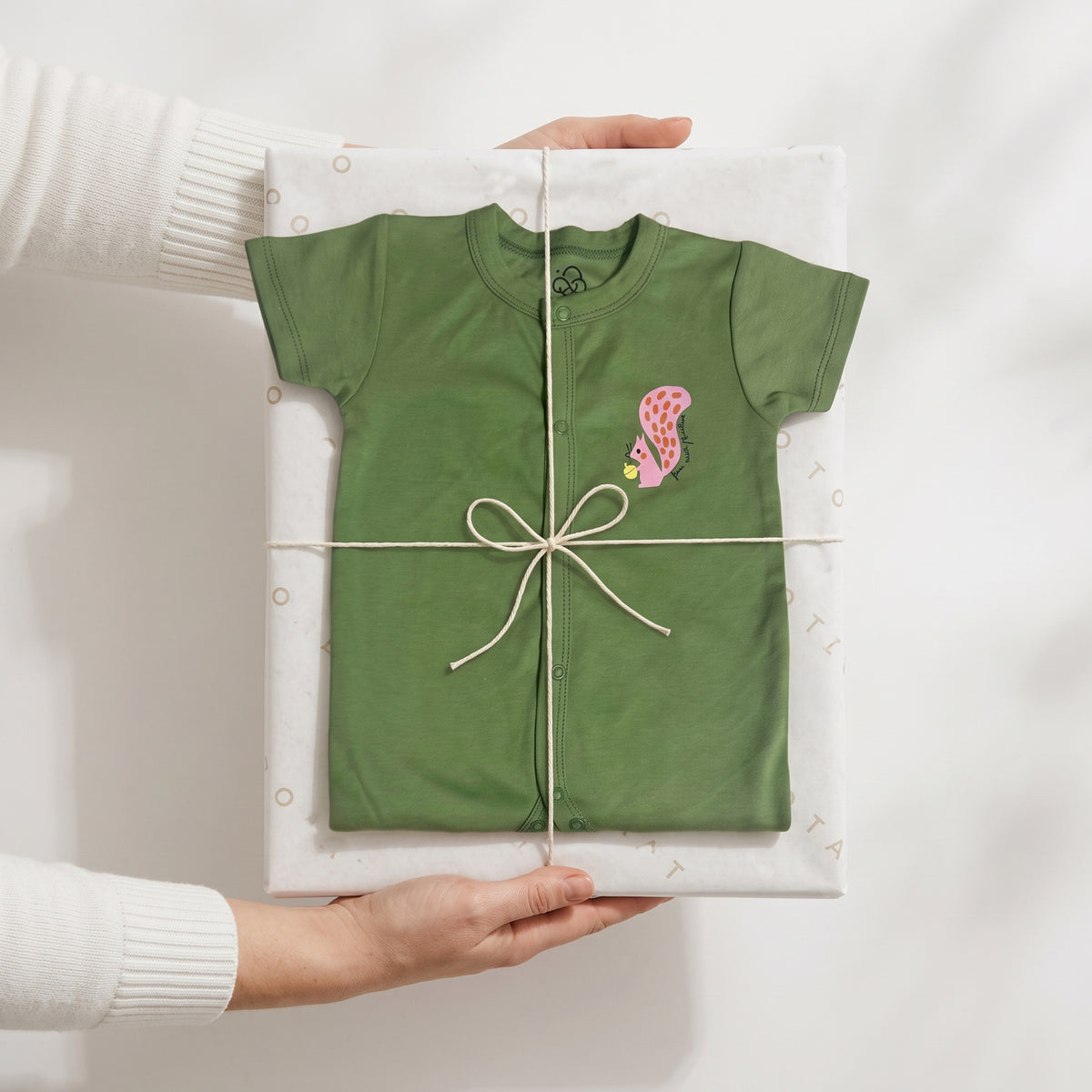 Folded olive-green Olive Grove jumpsuit wrapped in tissue and tied with string