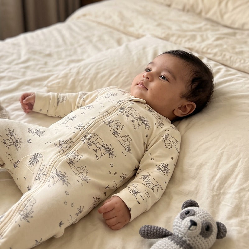 Baby in the Panda Cotton Jumpsuit in White Alyssum with a crochet panda toy