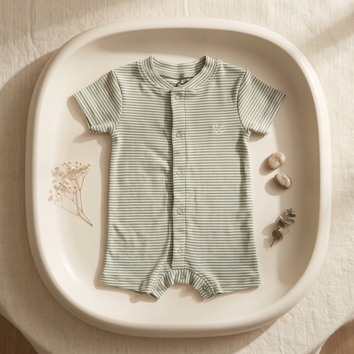 Green-striped short-sleeve romper laid flat, showing the front snaps and short legs